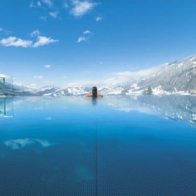 Alpinas Rooftop Pool mit Ausblick auf die verschneiten Berge