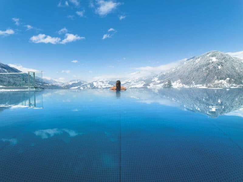 Alpinas Rooftop Pool mit Ausblick auf die verschneiten Berge